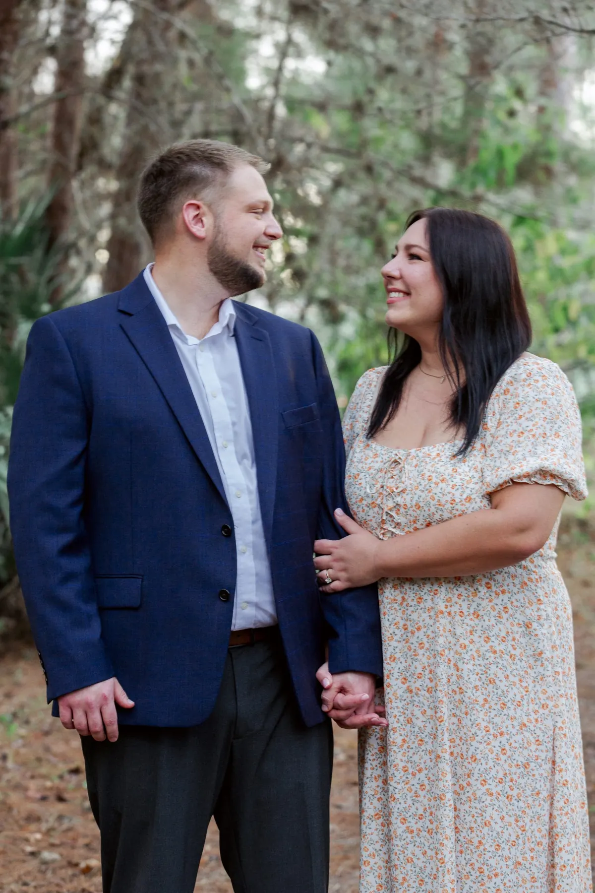 A couple smiling at each other under the oak trees