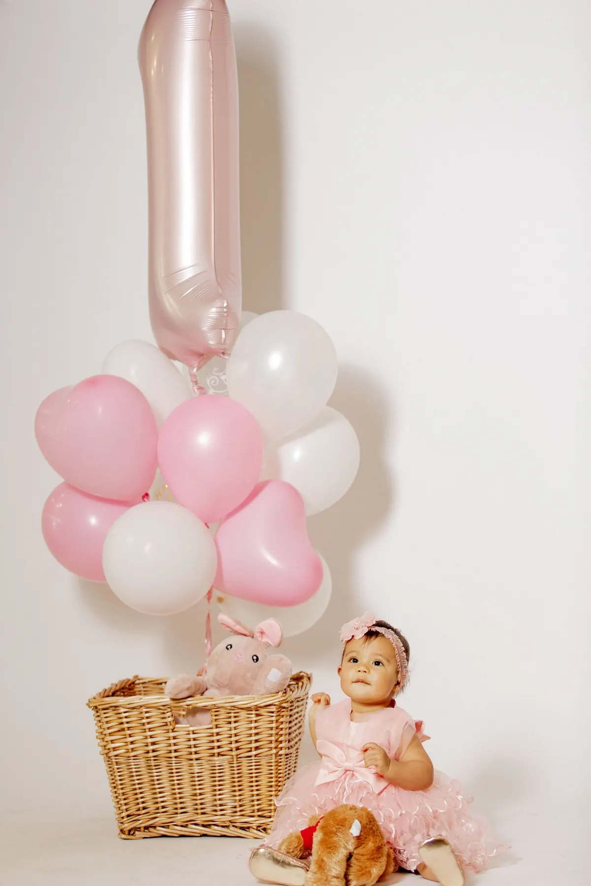 A baby girl at her first birthday with pink balloons