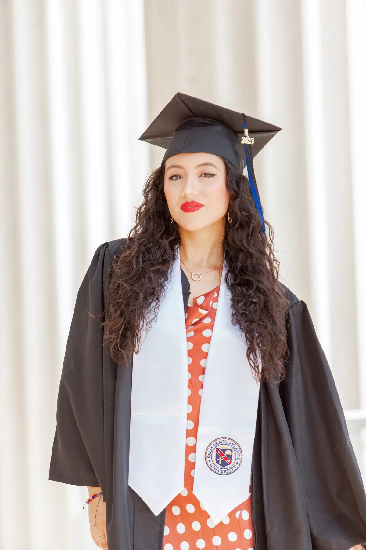 A graduate in cap, gown and stole smiling